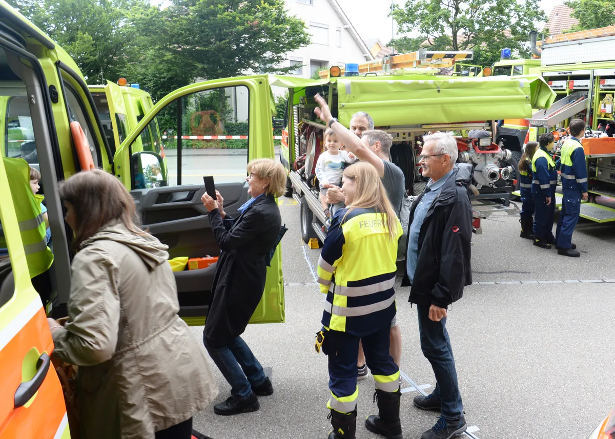 Mehrere Personen begutachten Feuerwehrautos. 